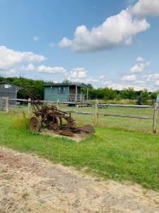 an old tractor sitting in a field next to a fence at Woodman's Rest in Kirdford