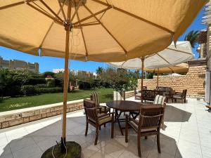 a table and chairs under an umbrella on a patio at Marina 7 4BR Villa lake view in El Alamein