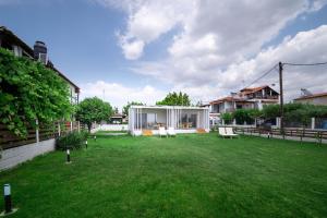 a yard with white chairs and a house at Thea Eco Suites in Nea Kallikrateia