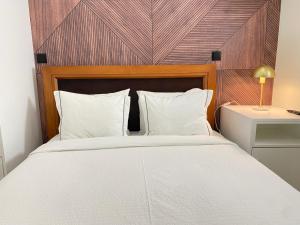 een slaapkamer met een wit bed en een houten hoofdeinde bij Canto Doce Troino II in Setúbal