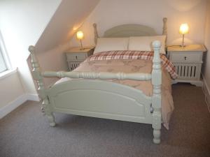 a bedroom with a white bed with two night stands at Aberlour Cottages - Bolthole & Retreat in Aberlour