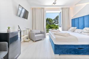 um quarto de hotel com uma cama grande e uma cadeira em Aurora Beachfront Luxury Rooms&Suites em Brela