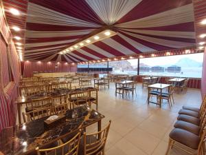 a restaurant with tables and chairs and a large ceiling at Harir Rum luxury camp in Wadi Rum
