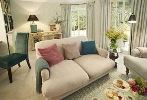 a living room with a white couch with colorful pillows at Pink Cottage in Shifnal