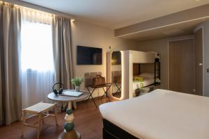 a hotel room with a bed and a table and a desk at ibis Golfe de Saint-Tropez in Cogolin