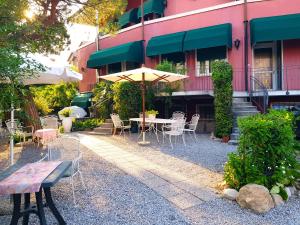 une table, des chaises et un parasol devant un bâtiment dans l'établissement Hotel Villa Pagoda, à Sirmione