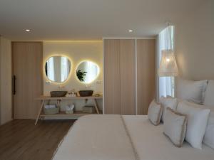 a bedroom with a large white bed and two mirrors at Retiro Costiña Wellness&villas in Santa Comba