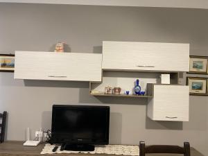 uma sala de estar com armários brancos e uma televisão em Appartamento Valamar Nikolla 2 camere em Hamallë