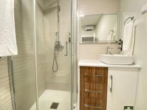 uma casa de banho com um chuveiro, um lavatório e um espelho. em Canto Doce Troino I em Setúbal