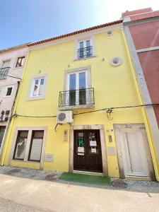 um edifício amarelo com duas portas e uma varanda em Canto Doce Troino I em Setúbal