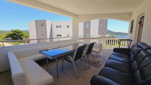 ein Wohnzimmer mit einem Sofa und einem Tisch auf dem Balkon in der Unterkunft Apartment house Berry in Primošten