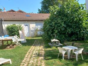 a garden with tables and chairs and a tree at Jacques et Paola Chanis in Ambérieu-en-Bugey