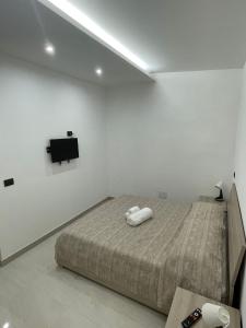ein weißes Zimmer mit einem Bett und einem Fernseher in der Unterkunft Il Pizzuto - Appartamento da Nonno Dino in Bernalda