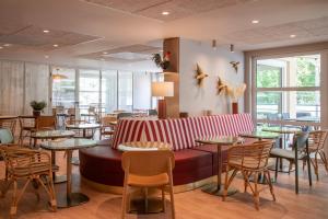 a restaurant with a couch and tables and chairs at ibis Golfe de Saint-Tropez in Cogolin