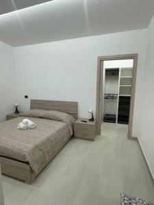 Un dormitorio blanco con una cama y un espejo. en Il Pizzuto - Appartamento da Nonna Anna, en Bernalda