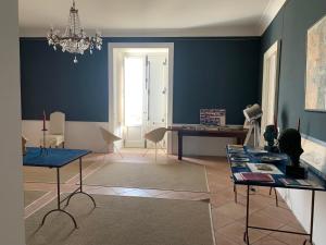 una sala de estar con paredes y mesas azules y una lámpara de araña. en Palazzo Carratelli, en Amantea