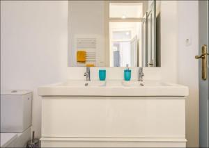 W białej łazience znajduje się umywalka i lustro. w obiekcie Zaire Retreat Apartment w Lizbonie