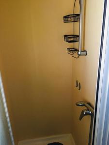a bathroom with a shower with three baskets on the wall at Mobil-home sur terrain privé in Sérignan