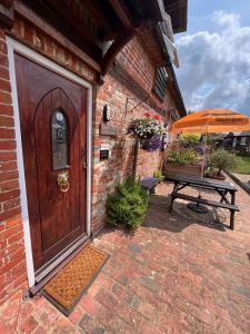 a wooden door and a picnic table with an umbrella at Hunston Mill Self Catering Dog Friendly in Chichester