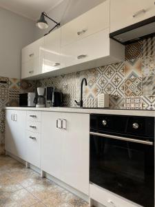 a kitchen with white cabinets and a black oven at Dolores in Giżycko