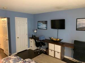 een kamer met een bureau en een televisie aan een blauwe muur bij The Redhawk Hideaway: Charming 2BR Condo near Miami Univ in Oxford! Book now! in Oxford