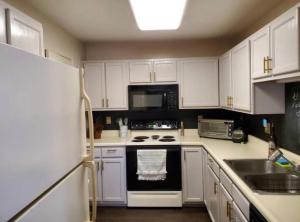cocina con armarios blancos y fogones negros en The Redhawk Hideaway: Charming 2BR Condo near Miami Univ in Oxford! Book now!, en Oxford