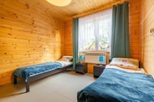 two beds in a room with wooden walls and a window at Domki nad morzem Ośrodek Baltica, Wicie in Wicie