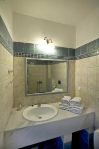 y baño con lavabo, espejo y toallas. en Assa Maris Beach Hotel en Pyrgadikia