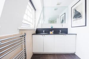 ein weißes Bad mit einem Waschbecken und einem Fenster in der Unterkunft Hyde Park Adventures in London