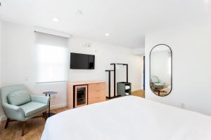 1 dormitorio con cama, silla y espejo en Grove Hotel, en Cherry Grove