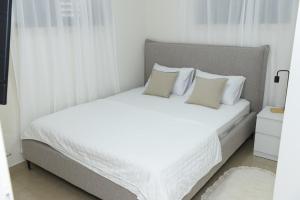 una camera da letto con un letto bianco con lenzuola e cuscini bianchi di יחידת קורל בלב הגליל העליון coral unit a Kiryat Shmona