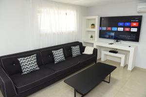 sala de estar con sofá negro y TV de pantalla plana en יחידת קורל בלב הגליל העליון coral unit en Qiryat Shemona
