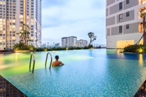 a person sitting in a swimming pool in a city at YO's Homes Rivergate Apartment Infinity Pool Near District 1 in Ho Chi Minh City