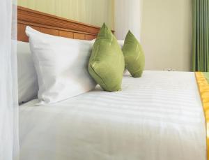 two green pillows sitting on top of a bed at Excelsis Garden Hotels - Kampala in Kampala