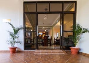 a lobby with large glass doors and two plants at Excelsis Garden Hotels - Kampala in Kampala