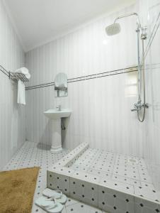 a white bathroom with a shower and a sink at Excelsis Garden Hotels - Kampala in Kampala