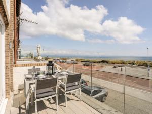 a table and chairs on a balcony with a view of the ocean at 7 Min Y Traeth in Pwllheli