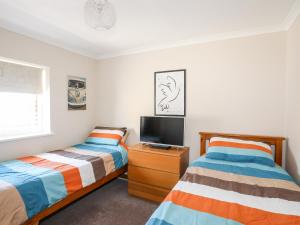 a bedroom with two beds and a tv on a dresser at 7 Min Y Traeth in Pwllheli