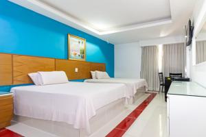 two beds in a room with blue walls at Hotel La Casona Dorada in Santo Domingo