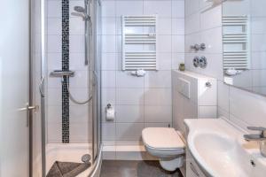 a bathroom with a shower and a toilet and a sink at Terrassenhaus, FeWo 22 in Duhnen