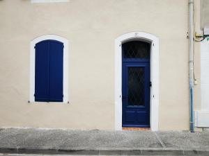 une porte bleue et deux fenêtres sur un bâtiment dans l'établissement Escapade détente au cœur de Pamiers, à Pamiers
