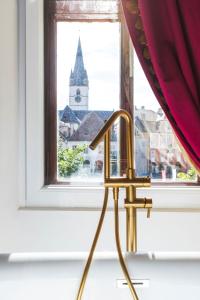 a gold chair in front of a window with a church at Sia Boutique Aparthotel in Sibiu
