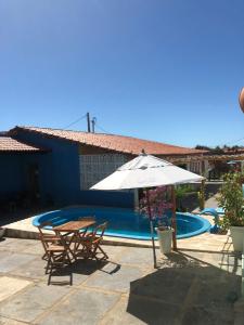 un patio con 2 sillas y una sombrilla junto a la piscina en Pousada Costa do Mar, en Luís Correia