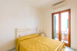 - une chambre avec un lit doté d'un couvre-lit jaune et d'une fenêtre dans l'établissement Friendly&Family Apartment at Ischia, à Ischia
