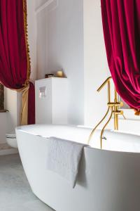 a bathroom with a white tub and red curtains at Sia Boutique Aparthotel in Sibiu
