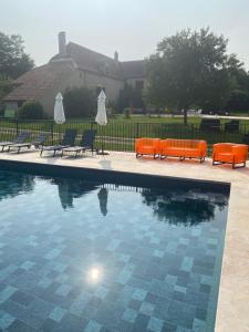 a swimming pool with two orange benches and chairs at Le Domaine du Gravier in Gramat