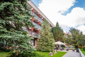 a building with trees and chairs in front of it at Majerik Hotel in Hévíz