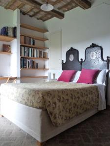 Un dormitorio con una cama grande con almohadas rosas. en Un giardino nel tufo, en Pitigliano