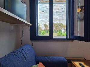 un divano blu in una stanza con finestra di Appartamento Dei Pini a Torre dell'Orso