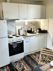 a kitchen with white cabinets and a stove at Funky Boho Kallithea Loft in Athens